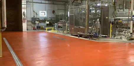 Industrial brewery facility with stainless steel equipment and freshly coated red epoxy flooring designed for sanitation and durability.