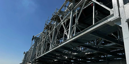 Close-up view of large industrial structural steel framework freshly coated in protective paint under a clear blue sky.